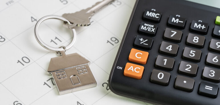 New house purchase, mortgage schedule reminder or real estate payment day, silver house keyring with calculator on white clean calendar