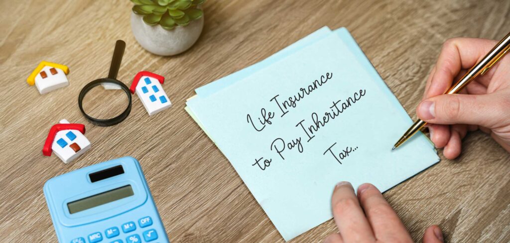 Life insurance to pay inheritance tax note with calculator and house models – estate planning and IHT protection strategy.